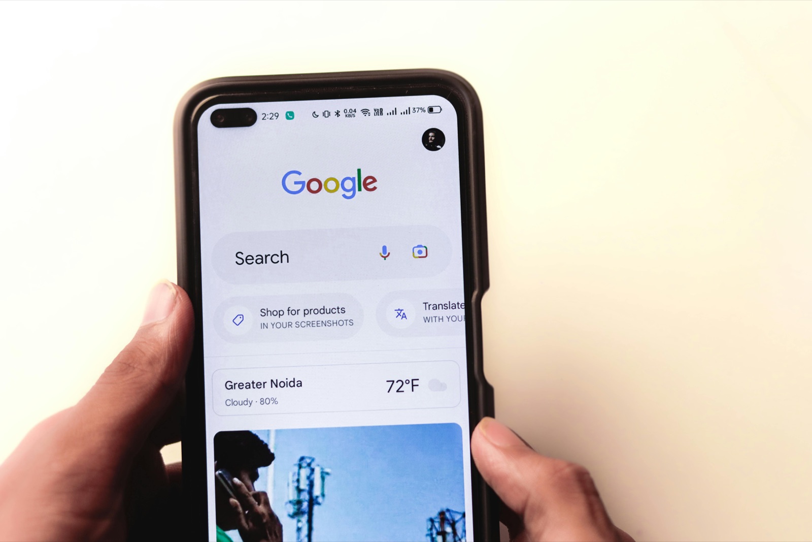 Two hands holding a phone open to a Google search