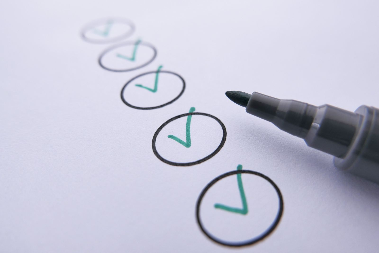 A column of hand-drawn checkmarks in circles on paper beside a marker pen