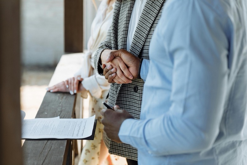 Two people shaking hands, one holding a clipboard